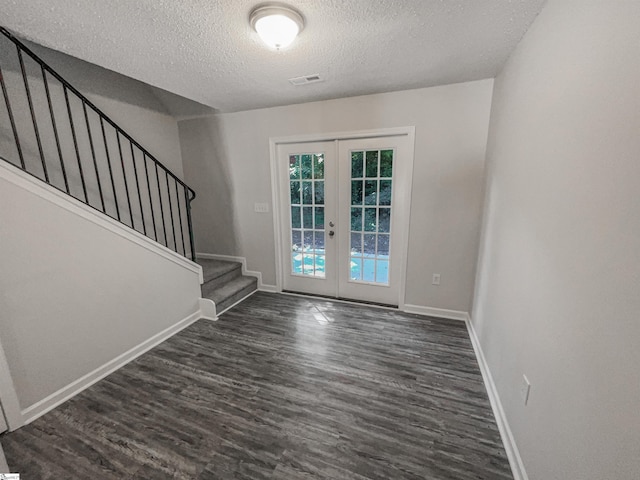 entrance foyer featuring a textured ceiling, dark wood-type flooring, and french doors