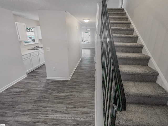 stairs with hardwood / wood-style flooring, sink, and a textured ceiling