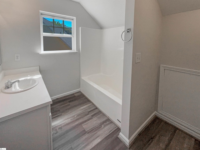 bathroom with hardwood / wood-style floors, vanity,  shower combination, and vaulted ceiling