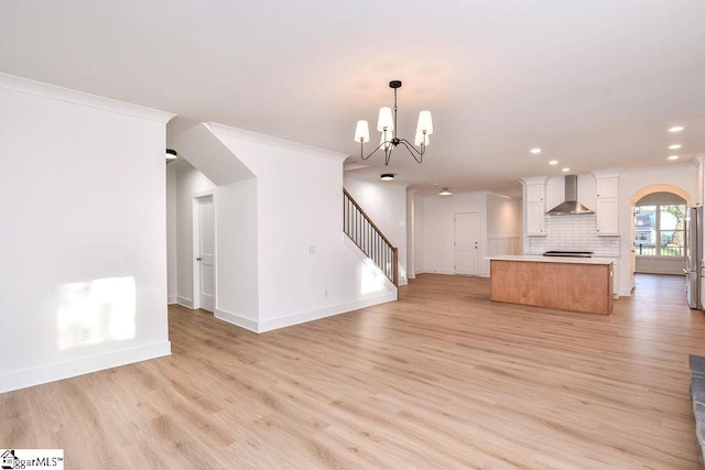 unfurnished living room with a chandelier, light hardwood / wood-style flooring, and ornamental molding