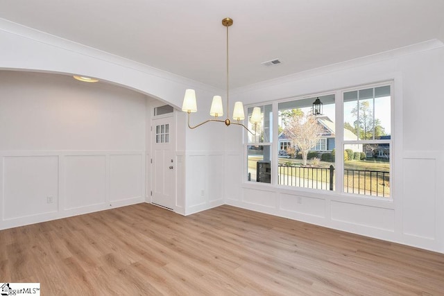 unfurnished dining area with light wood-type flooring, crown molding, and a chandelier