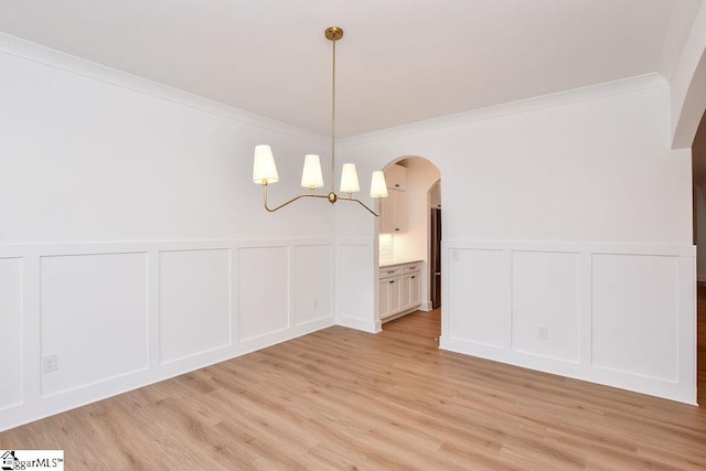 unfurnished dining area with light wood-type flooring and crown molding