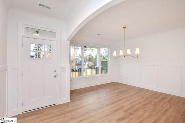 120 Club Cart Rd, Travelers Rest, SC 29690 - entryway featuring a decorative wall, light wood finished floors, a chandelier, arched walkways, and a wainscoted wall