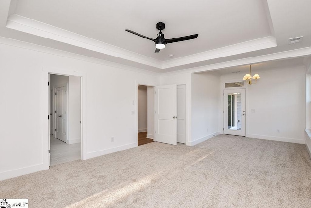 unfurnished room featuring ceiling fan with notable chandelier, light colored carpet, and a raised ceiling