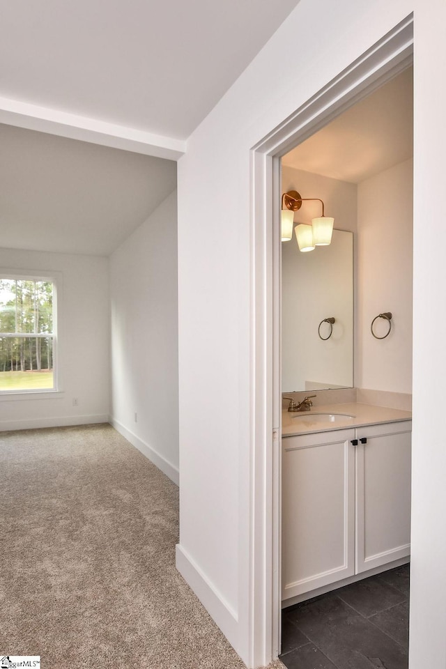 corridor featuring dark colored carpet and sink