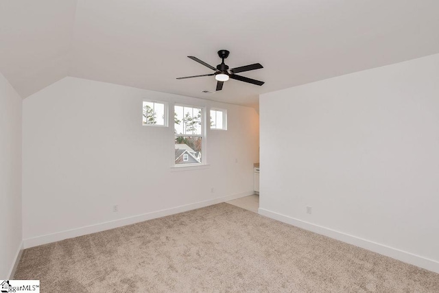 spare room with ceiling fan, light carpet, and vaulted ceiling