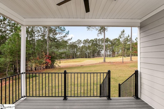 wooden terrace with ceiling fan and a yard