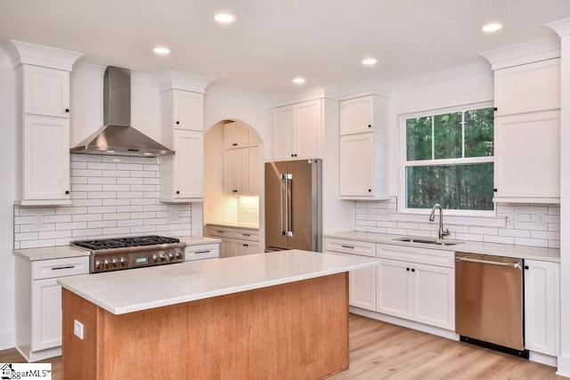 kitchen with sink, a center island, wall chimney range hood, and appliances with stainless steel finishes