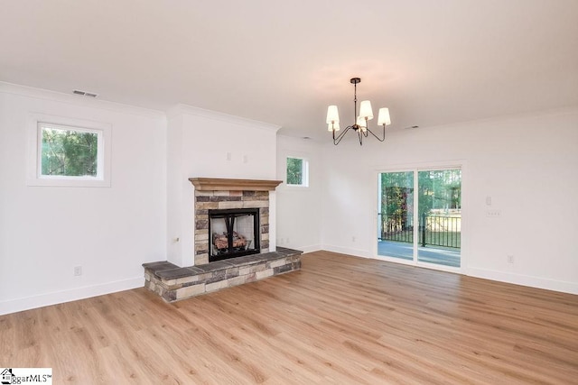 unfurnished living room featuring a chandelier, light hardwood / wood-style flooring, a stone fireplace, and crown molding