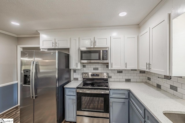 kitchen with tasteful backsplash, gray cabinetry, white cabinetry, and appliances with stainless steel finishes