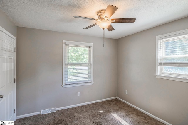 carpeted empty room featuring ceiling fan and a textured ceiling