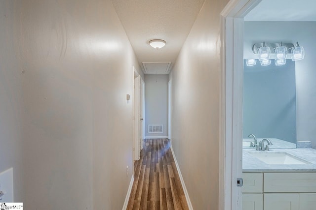 hall with hardwood / wood-style floors, a textured ceiling, and sink