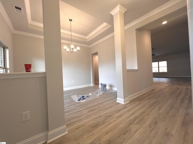 empty room featuring ornamental molding, a raised ceiling, visible vents, and wood finished floors