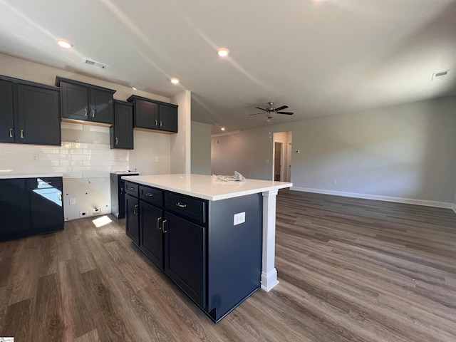 kitchen featuring dark wood-style floors, a kitchen island, open floor plan, light countertops, and backsplash