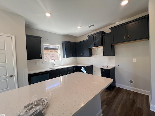 kitchen with sink, dishwasher, light stone counters, dark hardwood / wood-style flooring, and decorative backsplash