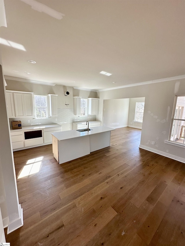 kitchen with dark wood-type flooring, sink, a kitchen island, a healthy amount of sunlight, and white cabinetry