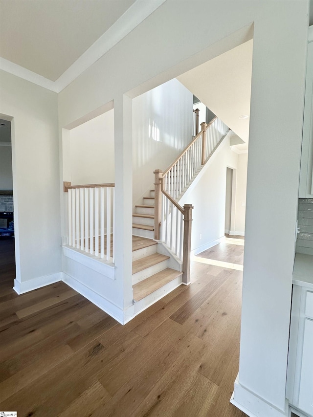 staircase with crown molding and hardwood / wood-style floors