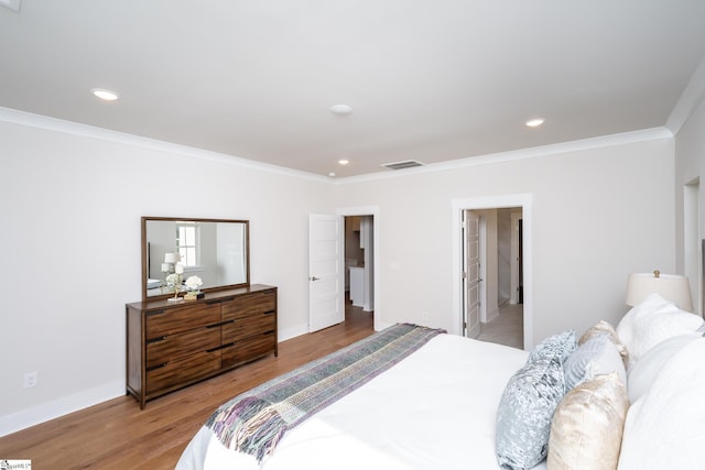 bedroom featuring light wood-type flooring, connected bathroom, and crown molding