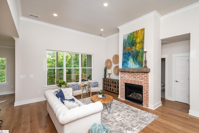 living room featuring hardwood / wood-style floors, a brick fireplace, and crown molding