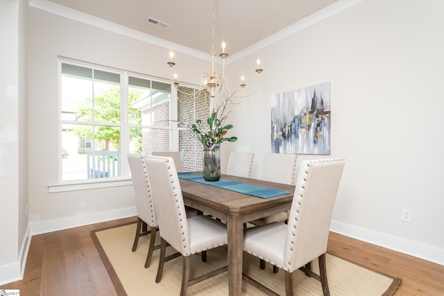 dining space featuring hardwood / wood-style floors, a healthy amount of sunlight, ornamental molding, and a chandelier