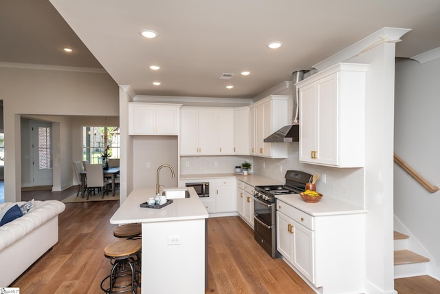 kitchen featuring a kitchen island with sink, sink, white cabinetry, black range with gas cooktop, and extractor fan