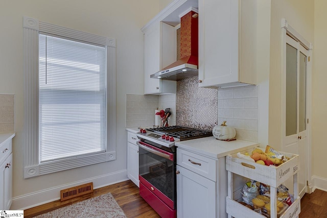 kitchen with stainless steel range, decorative backsplash, white cabinets, and wall chimney exhaust hood