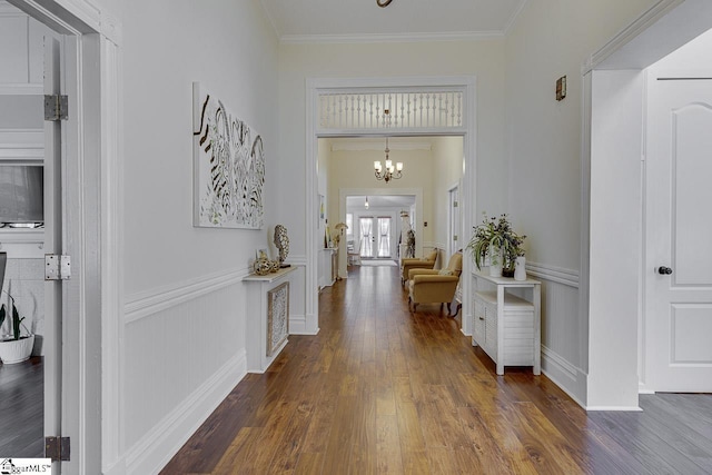 corridor featuring dark hardwood / wood-style flooring, ornamental molding, and an inviting chandelier