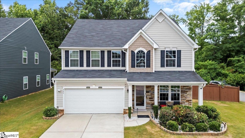 traditional-style home featuring a garage, stone siding, concrete driveway, and a front yard