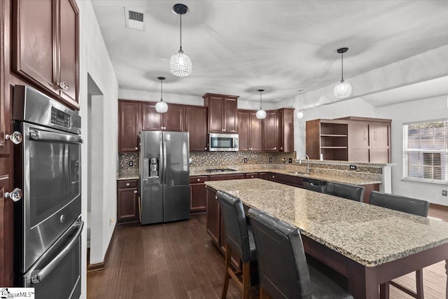 kitchen with pendant lighting, a center island, tasteful backsplash, a kitchen bar, and stainless steel appliances