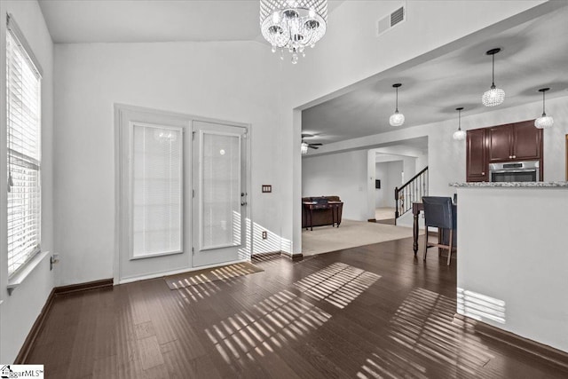 entrance foyer featuring ceiling fan with notable chandelier, dark hardwood / wood-style floors, and plenty of natural light