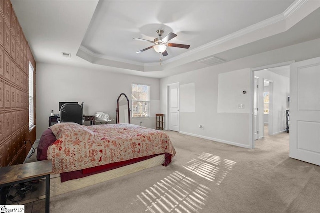 carpeted bedroom with a raised ceiling, multiple windows, ceiling fan, and ornamental molding