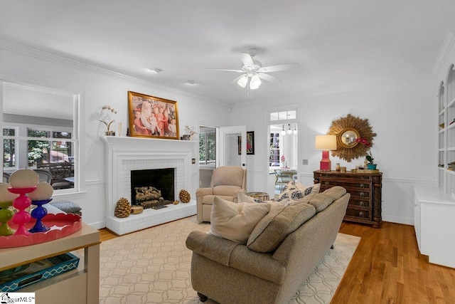 living room featuring ceiling fan, a fireplace, wood-type flooring, and ornamental molding