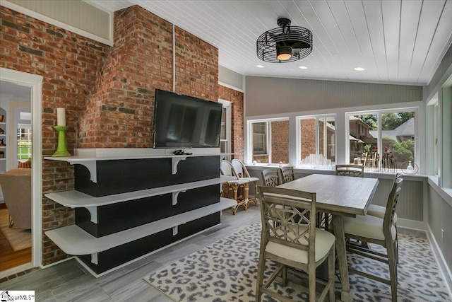 dining room with light hardwood / wood-style floors, wood ceiling, brick wall, and vaulted ceiling