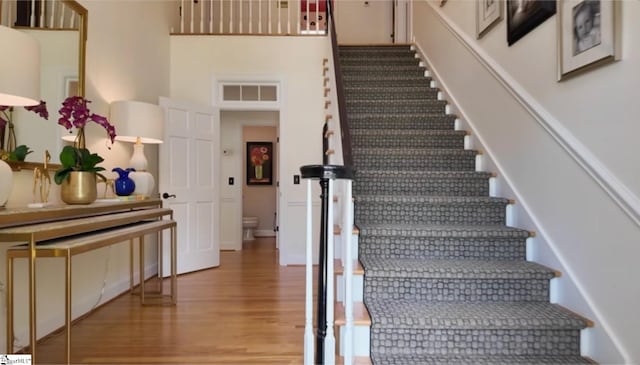 stairs with hardwood / wood-style flooring and a high ceiling