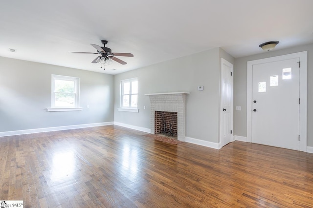 unfurnished living room with ceiling fan, dark wood-type flooring, and a brick fireplace