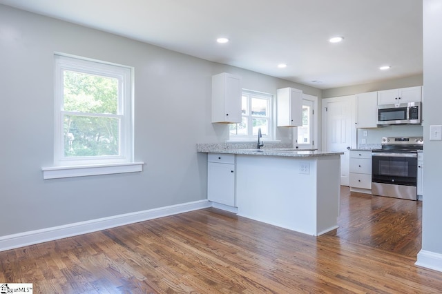 kitchen featuring white cabinetry, a healthy amount of sunlight, dark hardwood / wood-style floors, and appliances with stainless steel finishes