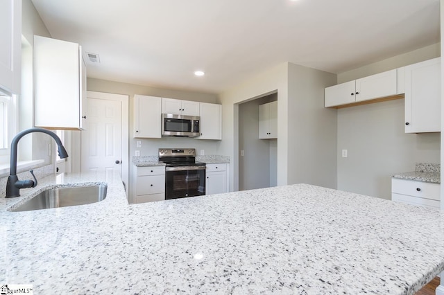 kitchen featuring light stone countertops, white cabinetry, sink, and appliances with stainless steel finishes