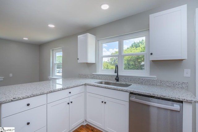 kitchen with light stone countertops, sink, stainless steel dishwasher, kitchen peninsula, and white cabinets