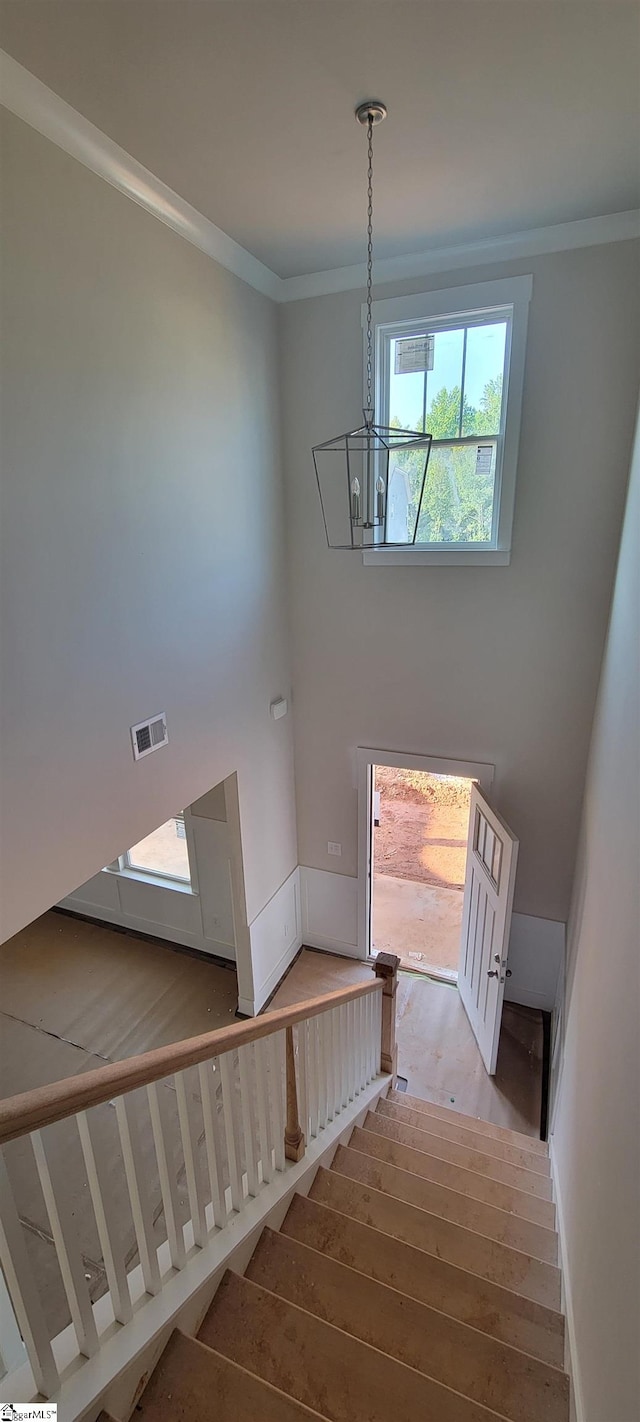 stairs with hardwood / wood-style flooring, an inviting chandelier, and ornamental molding