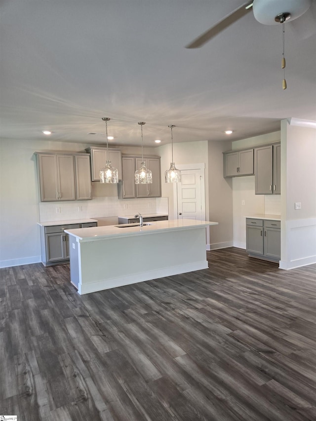 kitchen featuring recessed lighting, dark wood-type flooring, gray cabinetry, and a center island with sink