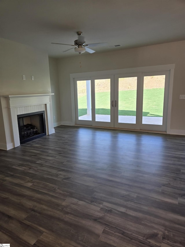 unfurnished living room featuring a tiled fireplace, dark wood-type flooring, and baseboards