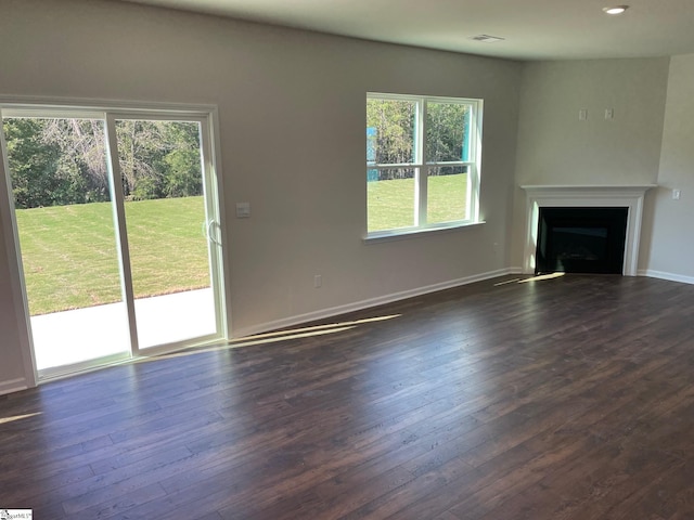 unfurnished living room featuring dark hardwood / wood-style flooring and a healthy amount of sunlight