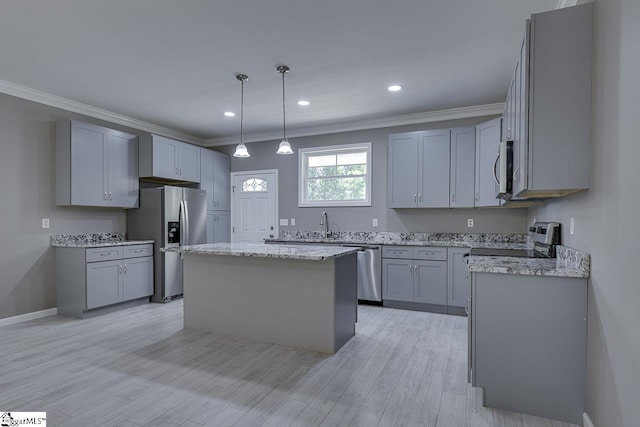 kitchen with ornamental molding, appliances with stainless steel finishes, decorative light fixtures, and a kitchen island