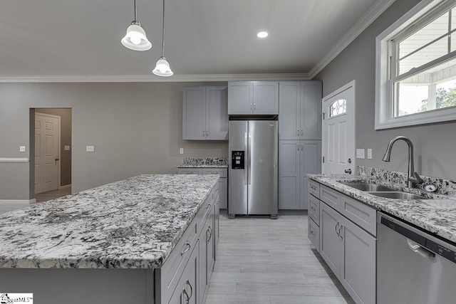 kitchen with gray cabinets, appliances with stainless steel finishes, sink, ornamental molding, and a center island