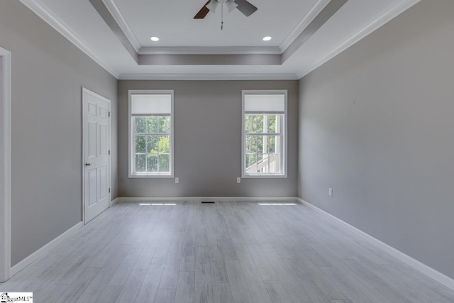 empty room featuring crown molding, ceiling fan, a raised ceiling, and light wood-type flooring