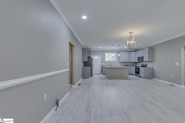 kitchen with hanging light fixtures, appliances with stainless steel finishes, a center island, and gray cabinetry