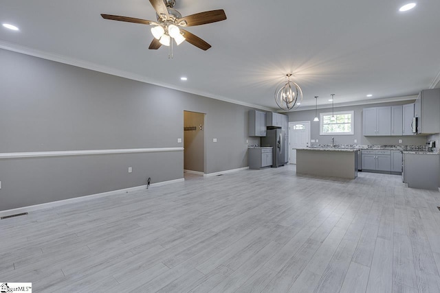 unfurnished living room featuring ornamental molding, sink, ceiling fan with notable chandelier, and light wood-type flooring