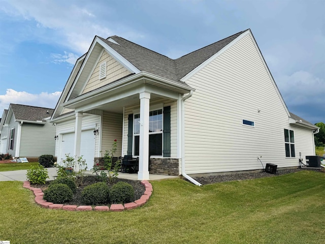 view of front of house featuring a porch, a garage, a front lawn, and central air condition unit