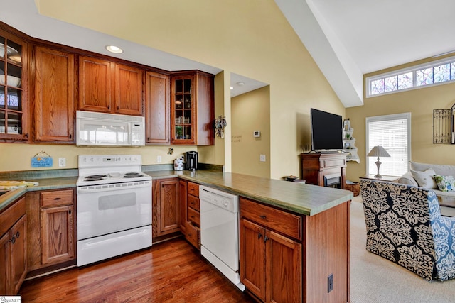 kitchen with dark wood-type flooring, white appliances, lofted ceiling, and kitchen peninsula