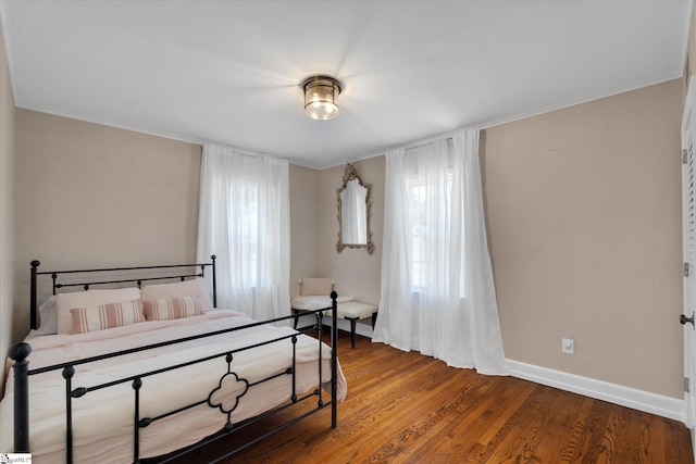 bedroom with multiple windows and hardwood / wood-style flooring